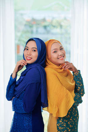 Pretty smiling young Vietnamese women in beautiful silk hijabs looking at cameraの写真素材