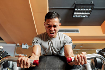 Asian young man doing fitness training on a butterfly machine with weights in a gym