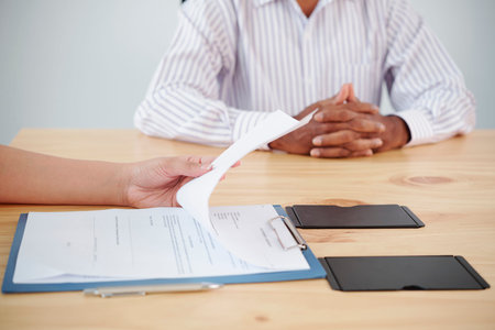 Close-up of female employee sitting at the table and reading a business contract with businessman...