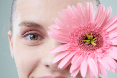 Beautiful face of young smiling woman and pink flowerの写真素材