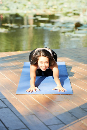 Pretty smiling young Asian woman stretching forward to relax after doing exercisesの写真素材
