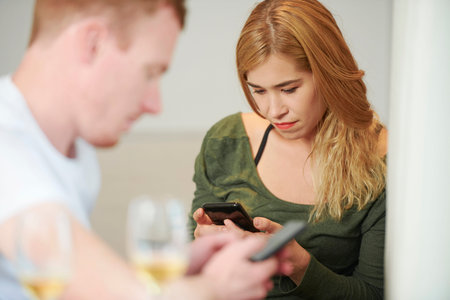 Serious young mixed-race woman texting friend or checking social media