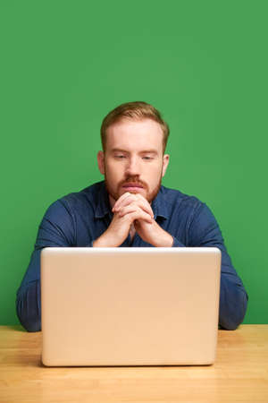 Portrait of young Irish businessman reading e-mail with important information on laptop screenの写真素材