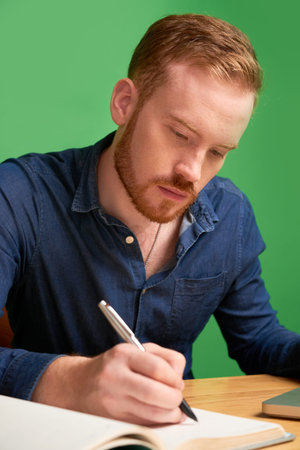 Portrait of young serious businessman filling his planner with appointments for the upcoming week