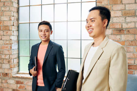 Happy handsome young startupper standing in new loft office next to his colleagueの写真素材