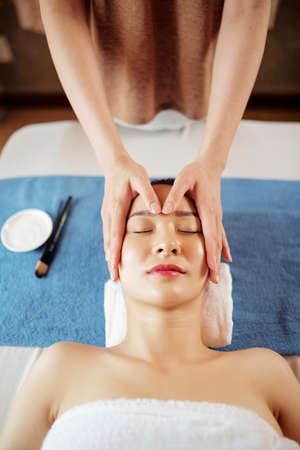 Cosmetologist making rejuvenating face massage with oils, view from aboveの写真素材