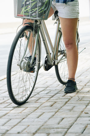 Cropped image of woman sitting on bicycle and resting after long ride in parkの写真素材