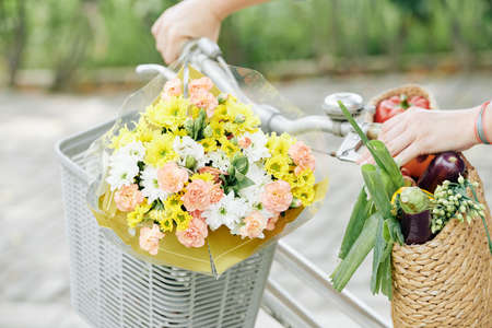Beautiful blooming flowers in bicycle basket of womanの写真素材
