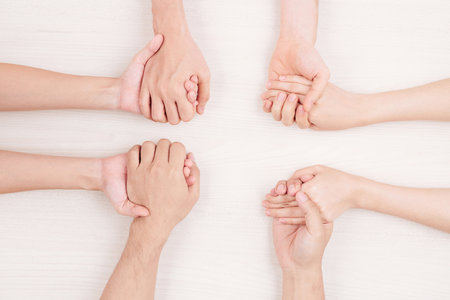 Close-up of young people sitting at the table and holding hands they support each other or playing...