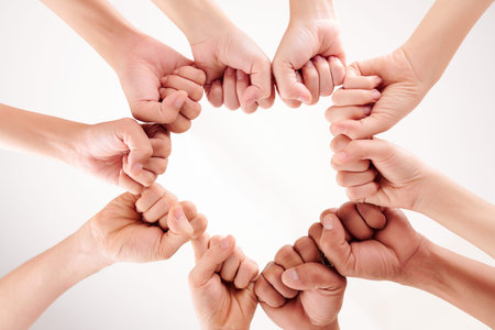 Close-up of multiethnic people making circle from arms and clenching their fists isolated on white...