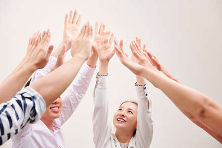 Young Asian people standing stretching their hands up and smiling they work in teamの写真素材