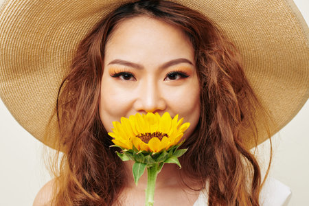 Fashion portrait of Asian model with red curly hair and with beautiful make-up wearing hat and...
