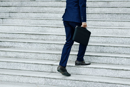 Cropped image of businessman with briefcase walking up the stairs outdoors