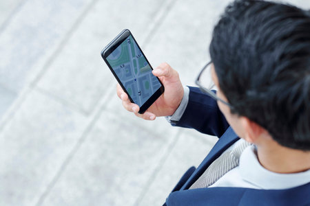 Businessman checking application on his smartwatch when waiting for taxi outdoors