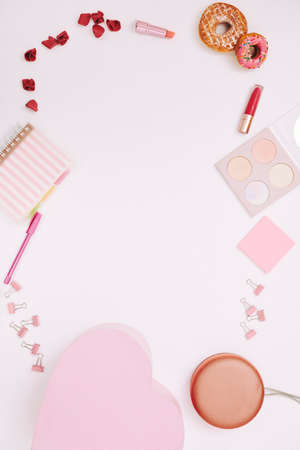Image of notepad lipstick sweet food and other female things in pink color making a frame around on white backgroundの写真素材