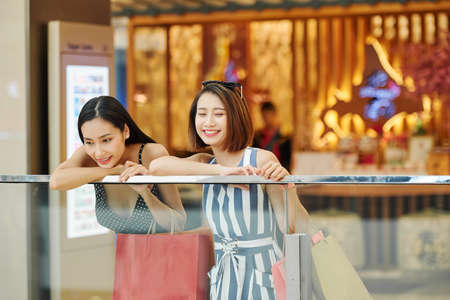 Two Asian young friends standing and smiling they spending funny time together in the shopping mallの写真素材