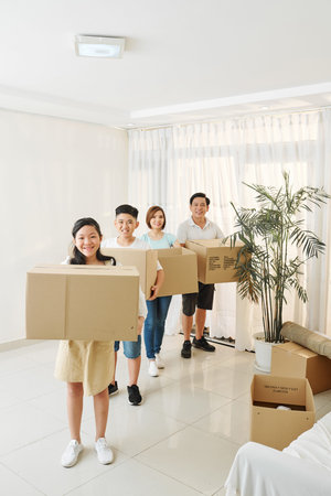 Parent and children holding cardboard boxes with belongings packed for house move