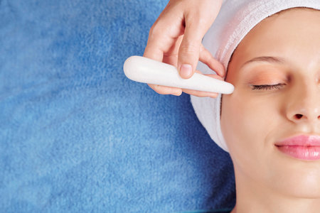 Close-up image of beautician using quartz stick to massage area around eyes and get rid of undereye wrinklesの写真素材