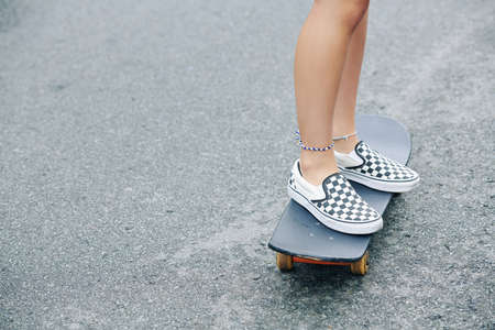 Feet of girl riding on skateboard on asphalt road in the cityの写真素材