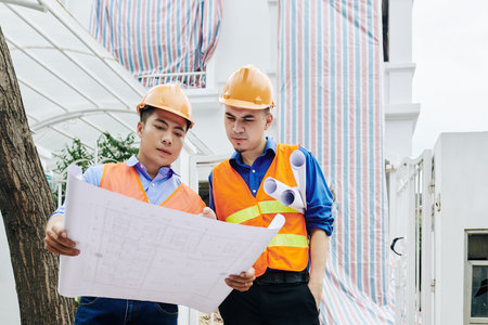 Serious construction workers discussing building layout before renovating house