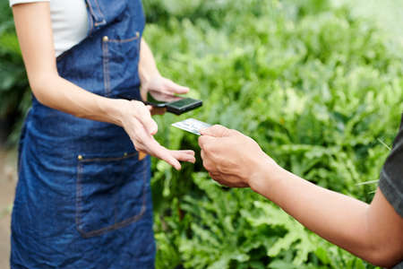 Customer giving credit card to greenhouse worker to pay for the plants he has chosenの写真素材