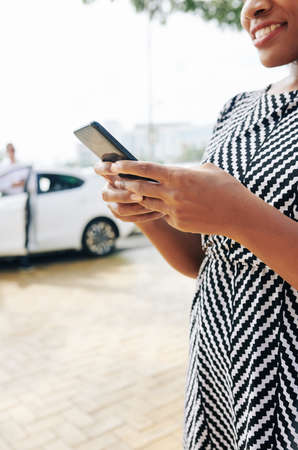Close-up of African woman standing in the city and using her mobile phone she order a taxi onlineの写真素材