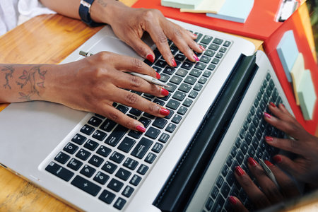 Close-up of businesswoman sitting at the table and typing on laptop computer she working online