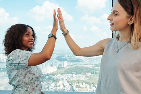 Smiling young businesswomen giving each other high five after productive meetingの写真素材