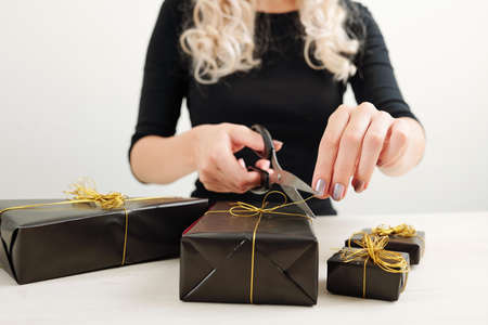 Close-up image of young woman wrapping presents in black paper for Halloween partyの写真素材