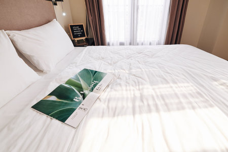 Opened magazine on queen bed in empty hotel room prepared for new guests