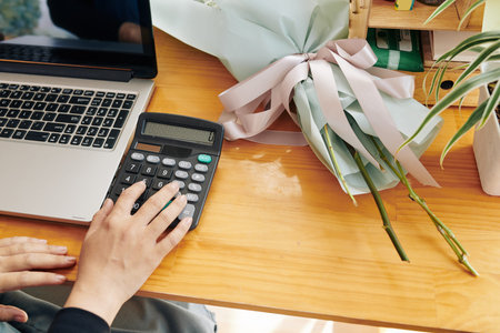 Florist using calculator when counting price of beautiful bouquet for customer