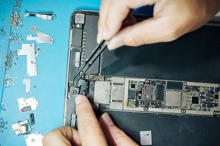Hands of manufacture worker showing process of establishing camera in tablet computerの写真素材