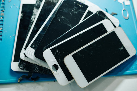 Cracked or broken removed smartphone screens on table of repairman, view from aboveの写真素材