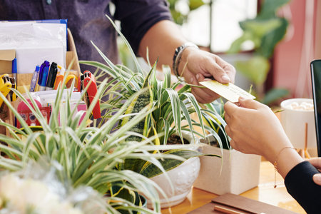 Hands of customer paying for purchase in flower shop with credit card