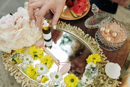 Woman taking bottle of essence and massage roller from silver tray on her vanityの写真素材