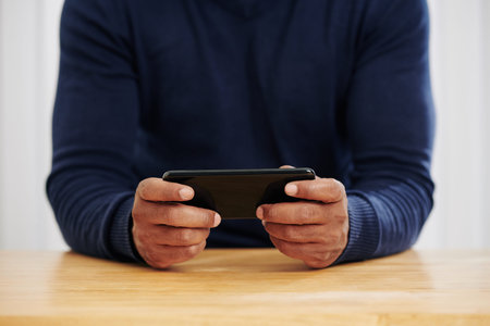 Hands of man sitting at office table and using application on smartphone