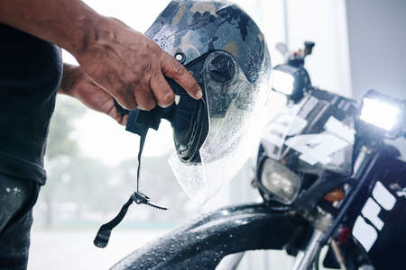 Hands of motorcyclist putting on helmet before driving in the cityの写真素材