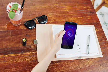 Woman checking humidity level via weather application on smartphone screen, view from aboveの写真素材
