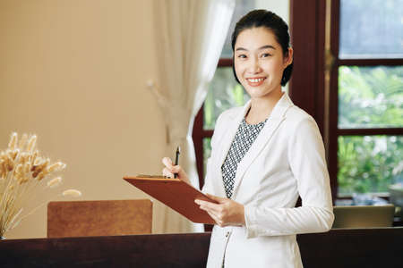 Portrait of lovely spa salon manager taking notes in document on clipboard in her handsの写真素材