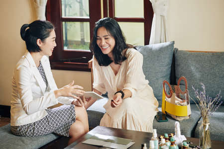 Cosmetics consultant showing new products to female client when visiting her at homeの写真素材