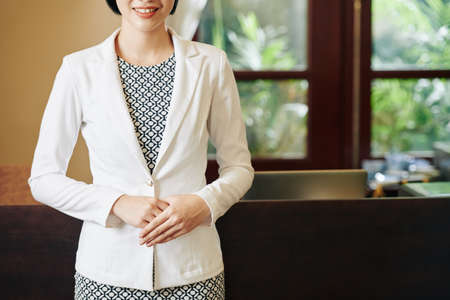 Cropped image of smiling receptionist in neat clothes greeting you in spa salon or boutique hotelの写真素材