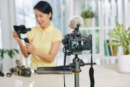 Digital camera shooting video of female blogger reviewing video production equipmentの写真素材