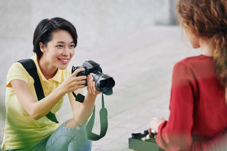 Pretty smiling young woman enjoying taking photos on pretty model outdoorsの写真素材
