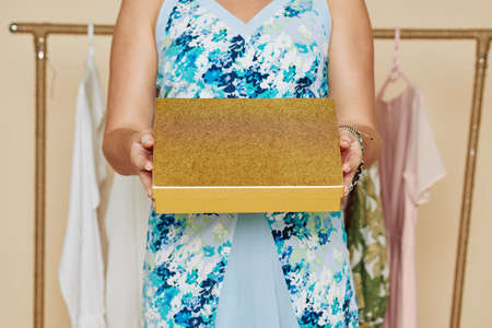 Woman standig in her closed and showing golden box with expensive bag or jewelryの写真素材