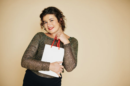 Portrait of pretty young woman just received New Year or Christmas present in small paper-bagの写真素材