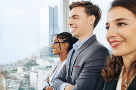 Happy young multi-ethnic business team looking through big office windowの写真素材
