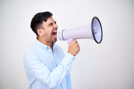 Studio shoot of young entrepreneur making announcement and shouting in megaphoneの写真素材