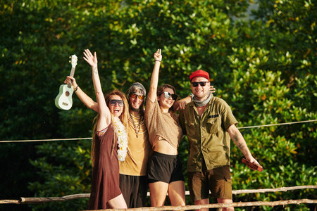 Group of happy excited friends in sunglasses raising hands and enjoying summer vacationの写真素材