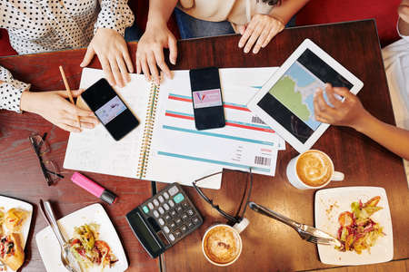Female friend having lunch in cafe, making plans and discussing upcoming trip, view from aboveの写真素材