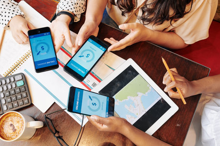 Group of female friends using banking application when paying for plane tickets and hotel...